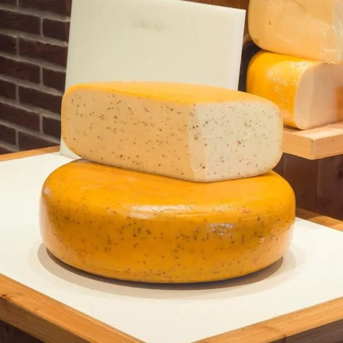 Cumin Gouda wheel with a cut half showing the seeds